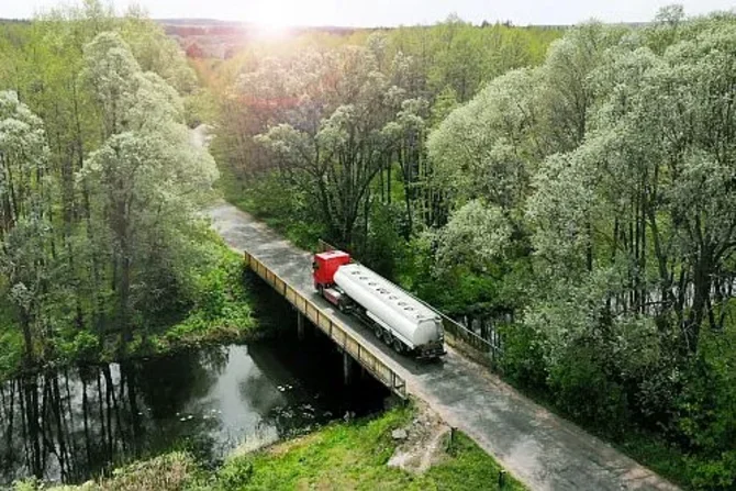 Lkw überquert eine alte Brücke Ein Lastkraftwagen fährt über eine ältere Brücke und überquert ein Gewässer.