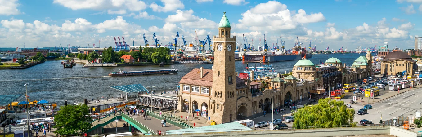 Luftbild Hamburger Hafen mit Speicherstadt, Kränen, Schiffen und historischen Gebäuden bei blauem Himmel.