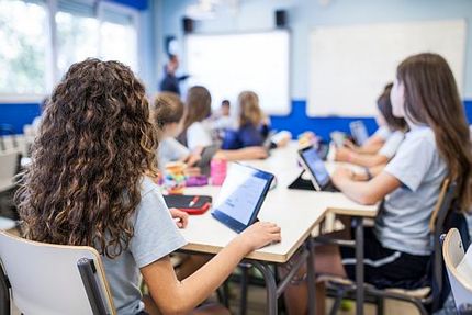 Schülerinnen arbeiten in einer Schulklasse an Tablets.