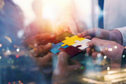 Foto: Business-Team hält unterschiedlich farbige Puzzleteile zusammen