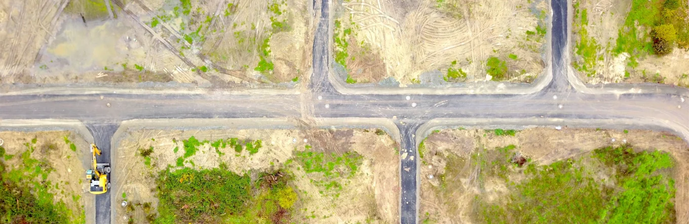 Luftbild eines erschlossenen Baugeländes mit neu angelegten Straßen und Bagger