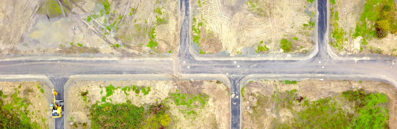 Luftbild eines erschlossenen Baugeländes mit neu angelegten Straßen und Bagger