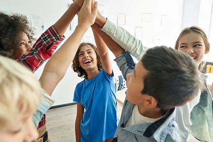 Mulitethnische Schüler geben sich High-Five im Klassenraum