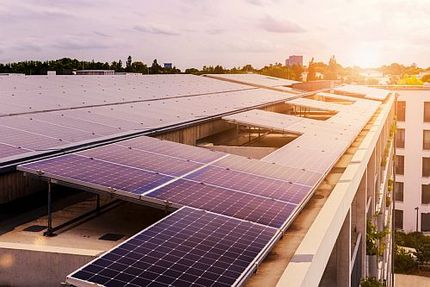 Solaranlage auf dem Dachen eines Mehrfamilienhauskomplexes mit der Skyline einer Stadt im Hintergrund.kgroung. M