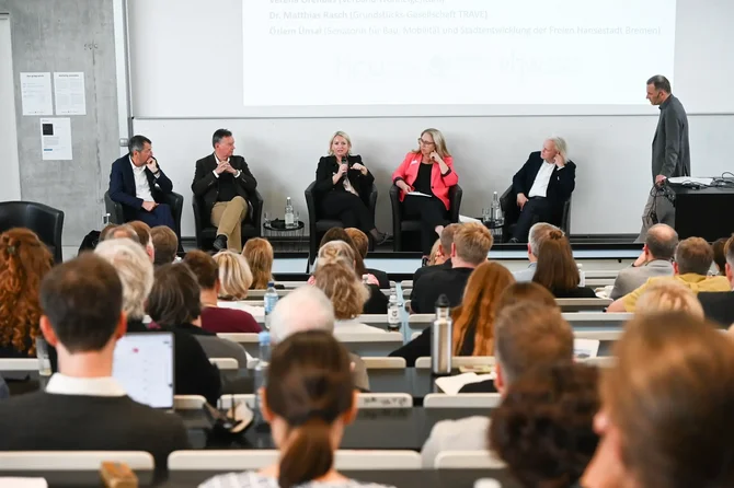 Podiumsdiskussion der Fachtagung "Neues Wohnen im Bestand", von links: Hilmar von Lojewski (Deutscher Städtetag), Axel Gedaschko (Bundesverband deutscher Wohnungs- und Immobilienunternehmen), Verena Örenbas (Verband Wohneigentum), Özlem Ünsal (Senatorin für Bau, Mobilität und Stadtentwicklung der Freien Hansestadt Bremen), Dr. Matthias Rasch (Grundstücks-Gesellschaft TRAVE) und Moderator Marcus Menzl (TH Lübeck)