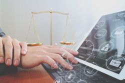 Foto zur Symbolisierung von elektronischem Rechtsverkehr – Person am Computer, im Hintergrund eine Waage als Symbol für Rechtsprechung
