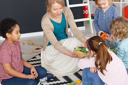 Multiethnische Kinder sprechen mit Erzieherin im Kindergarten 