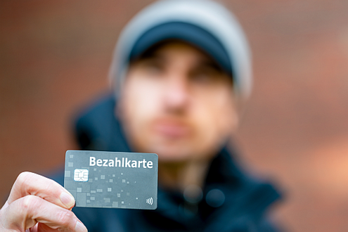 Mann hält Bezahlkarte in die Kamera.