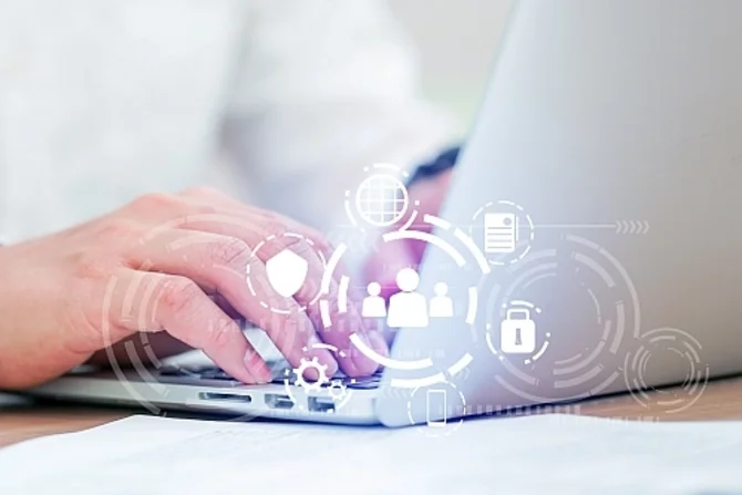 Digitale Personenauskunft und Datenschutz Eine Person sitzt an einem Laptop. Davor befindet sich ein hologrammartiges Display mit mehreren Symbolen, darunter ein Schild, ein Schloss und Personen.