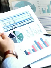 Detailansicht einer Finanzauswertung mit Kreisdiagramm, Balkendiagramm und Zahlentabellen neben Laptop