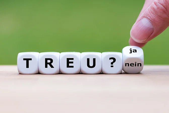 Eine Person bringt Würfel in eine bestimmte Reihenfolge. Die Symbole auf den Würfeln ergeben „Treu?“. Der letzte Würfel zeigt die Aufschrift „Ja/Nein“. Es ist nicht erkennbar, welche der beiden Optionen am Ende gewählt wird.