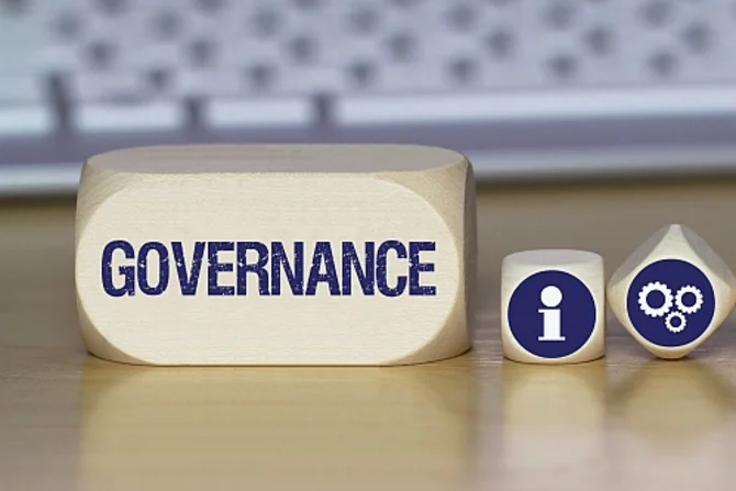 Governance und öffentliche Verwaltung Im Hintergrund ist eine Tastatur zu sehen. Davor befindet sich ein rechteckiger Würfel mit der Aufschrift „Governance“. Rechts davon liegen zwei kleine Würfel.