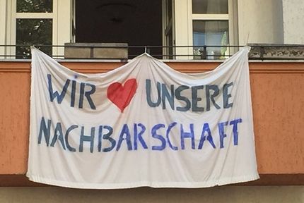 ©vhw/Olaf Schnur Ein Transparent, das an einem Balkon befestigt wurde auf dem steht: Wir lieben unsere NAchbarschaft