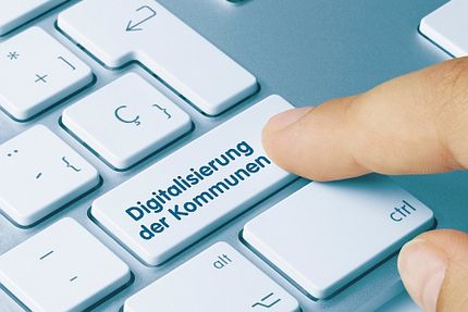 Foto: Finger tippt auf Taste einer Computertastatur mit Aufschrift "Digitalisierung der Kommunen". 