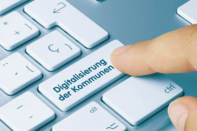 Digitalisierung der Kommunen Eine Tastatur mit einer Taste mit der Beschriftung „Digitalisierung der Kommunen“. Eine Person ist kurz davor, diese Taste zu drücken.