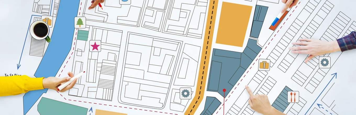 Mehrere Personen planen gemeinsam an Stadtplan mit farbigen Markierungen und Symbolen.