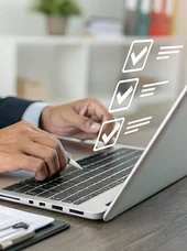 Zertifikatslehrgang "Fachkraft Fördermittelmanagement in der öffentlichen Verwaltung" Eine Person sitzt an einem Laptop. Vor dem Bildschirm des Laptops ist ein hologrammartiges Display zu erkennen.