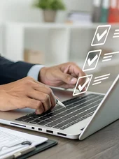 Eine Person sitzt an einem Laptop. Vor dem Bildschirm des Laptops ist ein hologrammartiges Display zu erkennen.