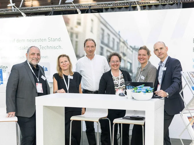 Messe KOMMUNAL Erfurt Kolleginnen und Kollegen des vhw stehen freundlich lächelnd an ihrem Messestand.