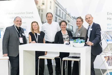 Kolleginnen und Kollegen des vhw stehen freundlich lächelnd an ihrem Messestand.