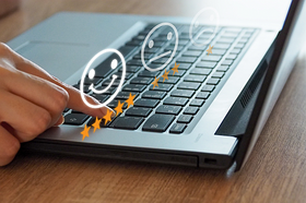 Foto: Frau gibt am Laptop 5-Sterne-Bewertung mit lachendem Smiley ab.