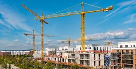 Wachsendes Stadtquartier mit Wohnhäusern im Rohbau, Baukränen und begrünten Erschließungsstraßen