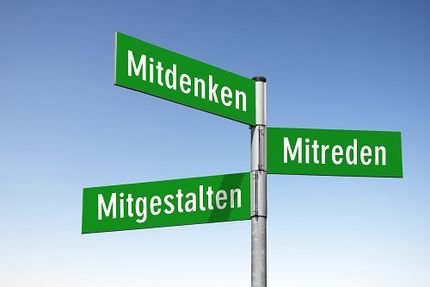 Drei Straßenschilder an einem Pfahl, die in verschiedene Richtungen zeigen. Aufschrift: Mitreden, Miteintscheiden, Mitgestalten