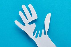 Illustration zum Thema Kinderbetreuung und Kinderrechte: kleine Hand ausgeschnitten in einer großen Papierhand vor blauem Hintergrund