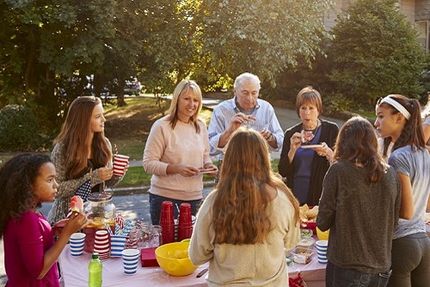 Menschen stehen draußen an einem Tisch mit Essen und Getränken