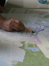 Zertifikatslehrgang Moderator SE Die Abbildung zeigt Menschen, die eine große Übersichtskarte analysieren, was zur Planung von Routen oder zur Orientierung im Gelände genutzt wird.
