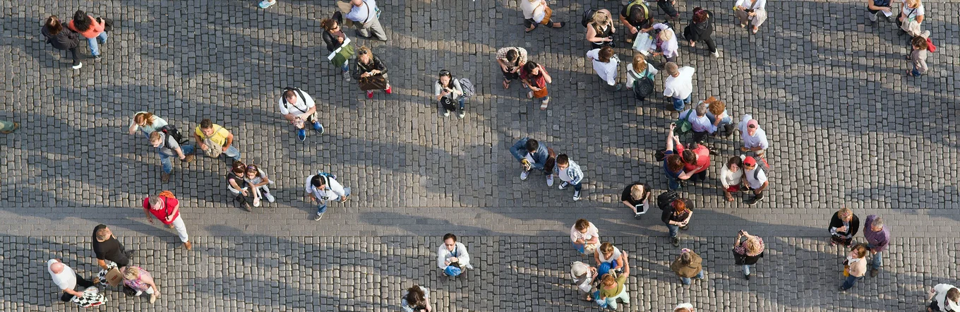Vogelperspektive auf diverse Personengruppen auf einem gepflasterten Platz