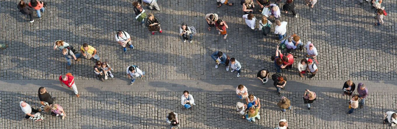 Vogelperspektive auf diverse Personengruppen auf einem gepflasterten Platz