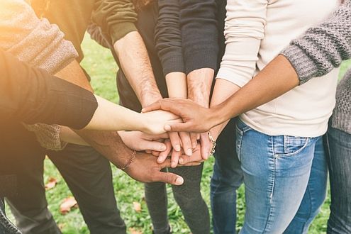 Junge Menschen unterschiedler ethnischer Herkunft legen Hände aufeinander