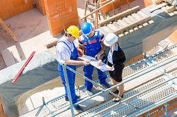 Bauleiter, Arbeiter und Architektin auf einer Baustelle.