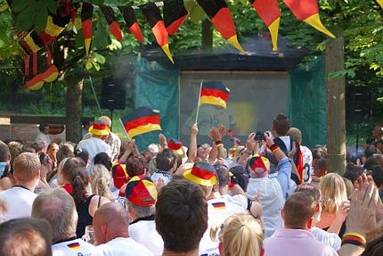 Fußballfans beim Public viewing vor ein Leinwand im öffentlichen Raum.