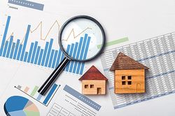  Symbolbild für eine Immobilienbewertung – Lupe auf Grafik zur Preisentwicklung bei Immobilien