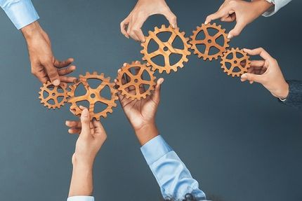 Hände, die Zahnräder halten, die ineinander greifen