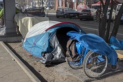 Stadtplanung und Soziale Stadtpolitik: Ein blaues Zelt, das auf einem Fußweg platziert ist und Armut in öffentlichen Raum darstellt.