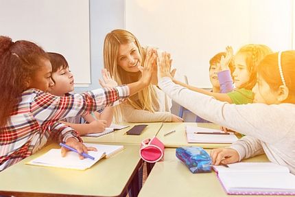 Foto: Eine Gruppe von Schülerinnen und Schülern gibt Betreuerin High Five.