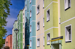 Foto einer Häuserzeile mit sanierten Mietshäusern des sozialen Wohnungsbaus mit unterschiedlich farbig gestalteten Fassaden.