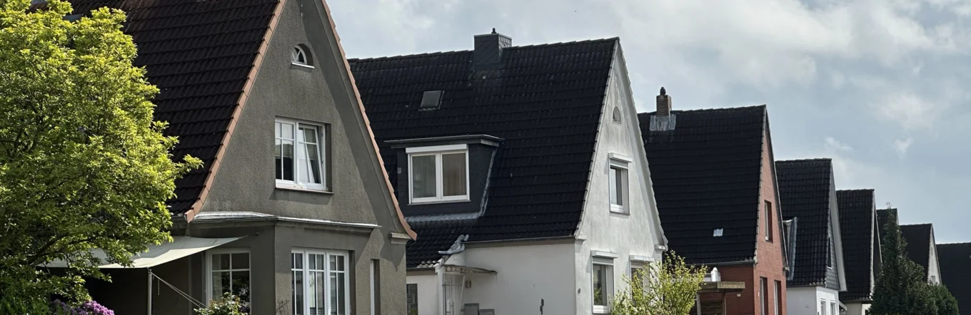 Einfamilienhaussiedlung mit Statteldächern und Vorgärten in norddeutscher Wohnstraße