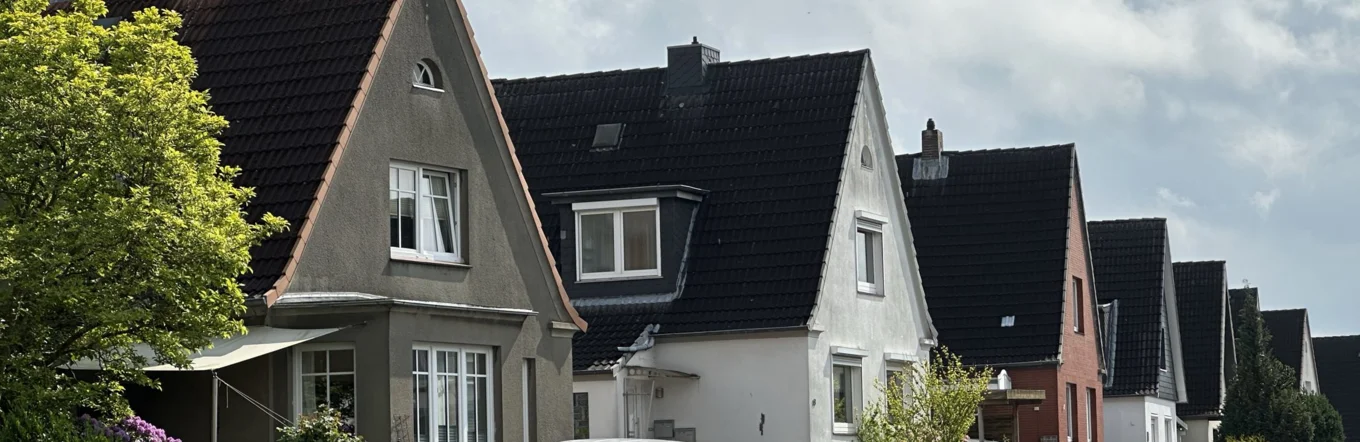 Einfamilienhaussiedlung mit Statteldächern und Vorgärten in norddeutscher Wohnstraße