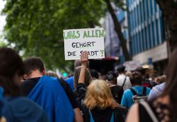 Bürgerbeteiligung bei der Stadtplanung. Menschen bei Demo mit Schildern mit der Aufschrift "Uns allen gehört die Stadt".