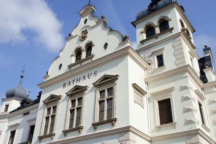 Historisches Rathaus mit Barockfassade, Türmen und Wappenschmuck bei Sonnenschein.