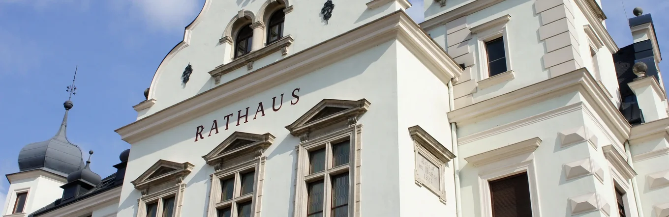 Historisches Rathaus mit Barockfassade, Türmen und Wappenschmuck bei Sonnenschein.