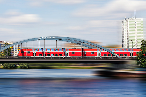 Regionalbahn überquert Fluss auf einer Eisenbahnbrücke.