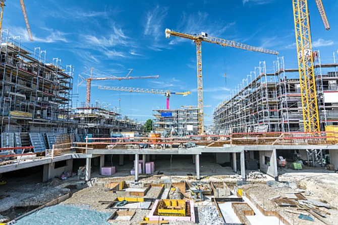 Großbaustelle im städtischen Raum Eine großflächige Baustelle mit Baukränen, Maschinen und Arbeiten im urbanen Umfeld.