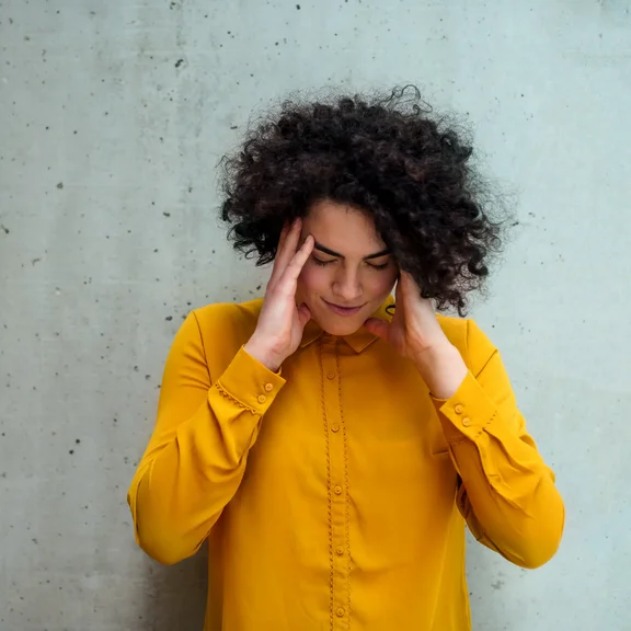 goING.mindful - Mindfulness als Schlüsselkompetenz für Führungskräfte im (öffentlichen) Bauwesen Frau hält sich mit geschlossenen die Hände an die Schläfen als Zeichen der Konzentration.