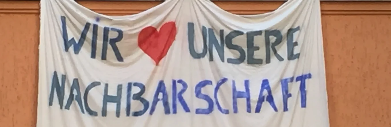Banner an Hausfassade mit der Aufschrift "Wir lieben unsere Nachbarschaft"