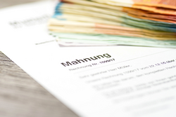 Foto: Mahnungsschreiben liegt unter einem Bündel von Geldscheinen
